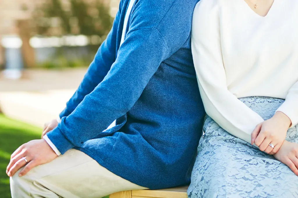 Couple sitting together on a wooden bench.