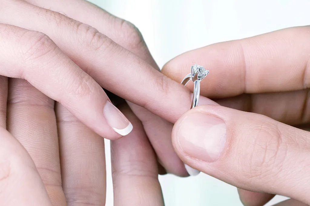 Person proposing with a diamond engagement ring.