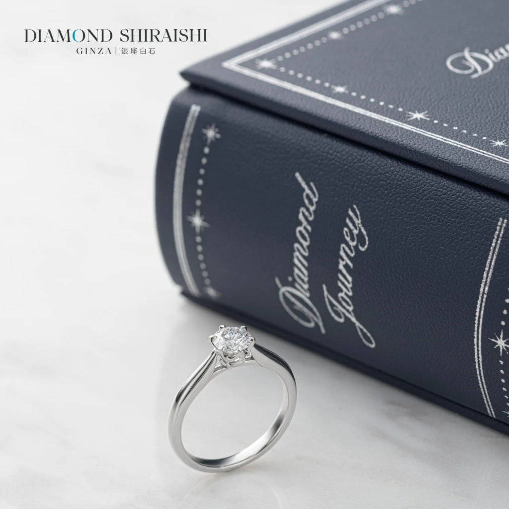 Silver engagement ring beside a book