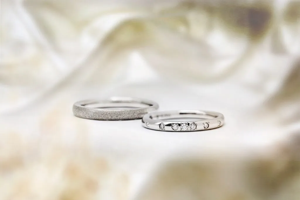 Two elegant silver rings on soft fabric background.